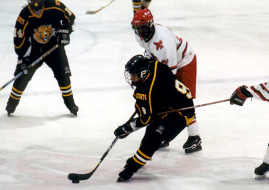 Lee Allen carries the puck between two Shaker Raiders.