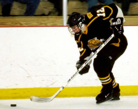 Andrew West moves the puck along the boards.